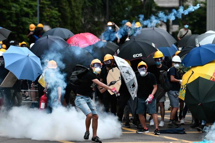 FOTO AFP EN HONG KONG. Los manifestantes se cubren de los gases con paraguas.