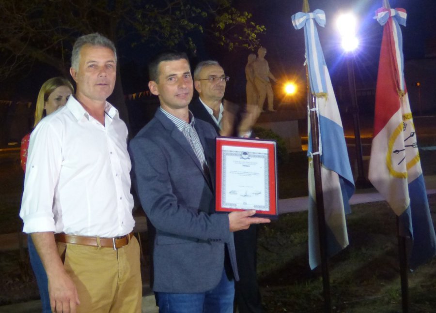 FOTO PRENSA OM// EN SAN ANTONIO.// Omar  Mart&iacute;nez y Mauro Previotto en la entrega de la Declaraci&oacute;n de Inter&eacute;s, observa , el senador Alcides Calvo. BANDERA./ Un emblema de ceremonia fue entregado por el legislador a autoridades del establecimiento.