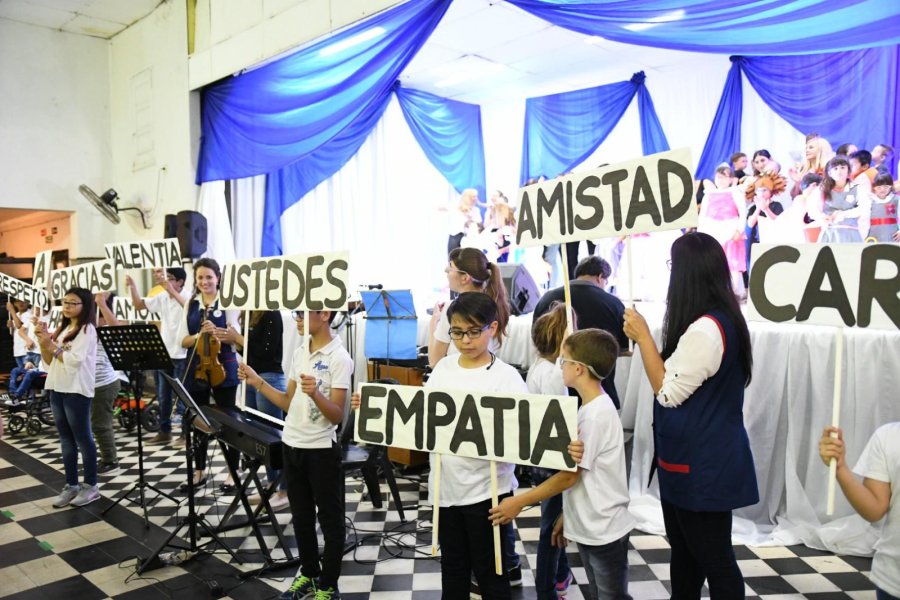 FOTO PRENSA MUNICIPAL CON LA TORTA. Alumnos, docentes y el intendente Castellano en la foto de la fiesta.  ACTO. Los chicos levantan distintos mensajes durante un momento del festejo.