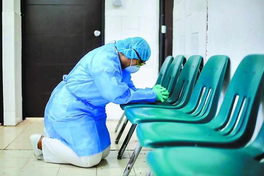 FOTO AP AGOTADA. Una enfermera paname&ntilde;a reza sobre una silla en un hospital.