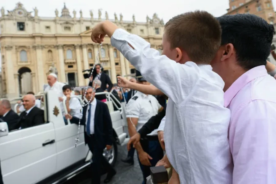 Un ni&ntilde;o exhibe un Rosario y saluda al Papa.