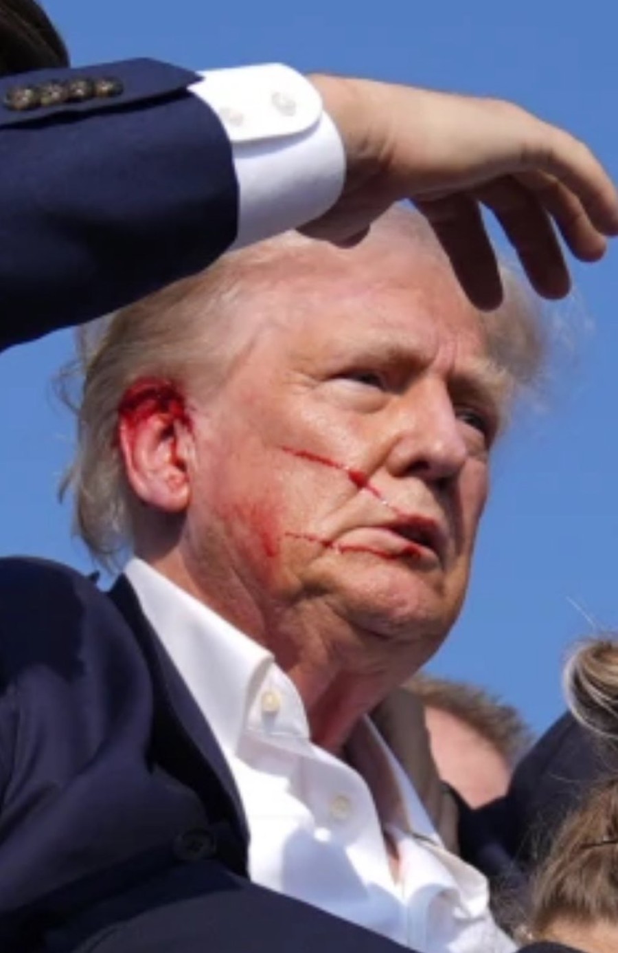 Trump con sangre en la oreja derecha y en su rostro.