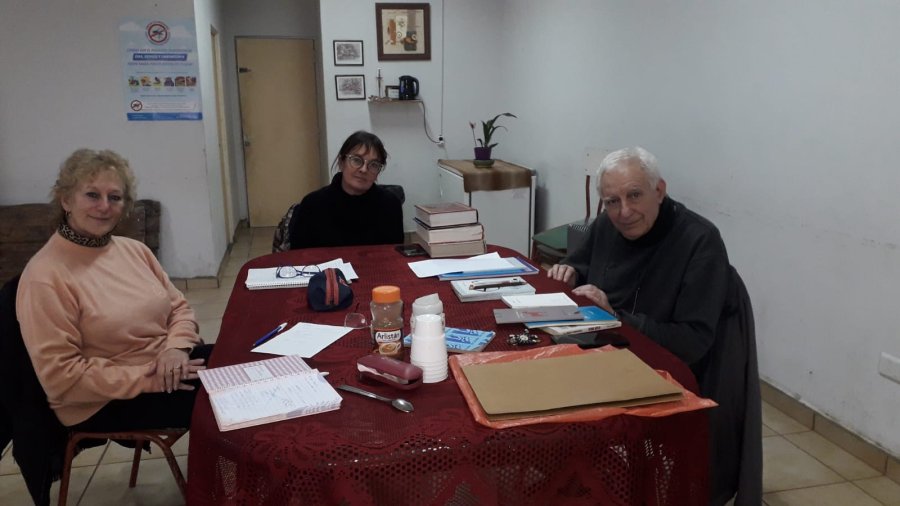 TALLER. Daiana, Milagros y Hugo Borgna alrededor de una mesa con varios libros en la Vecinal de barrio Italia.