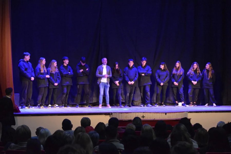 El elenco en el escenario, en el centro el director dirigi&eacute;ndose al p&uacute;blico.