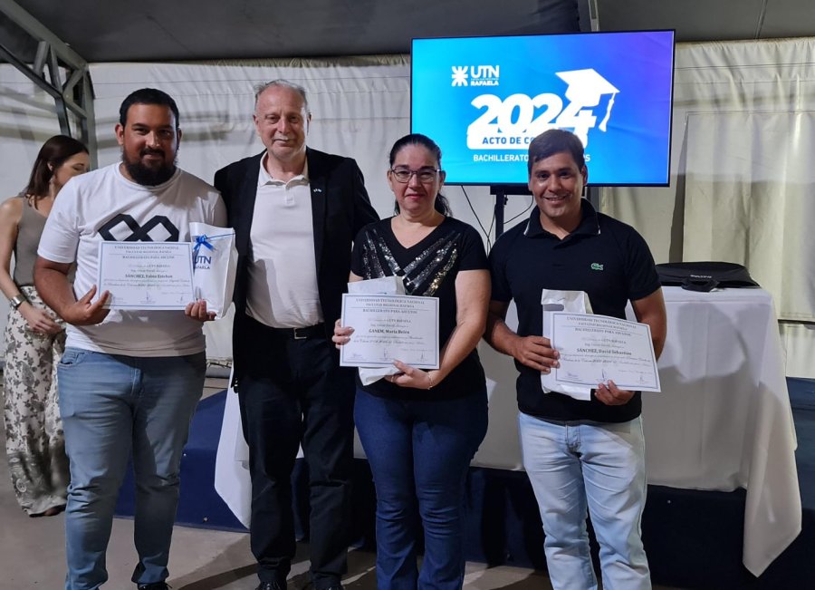 El secretario General de UTN FRRa, Ing. Orlando Thailinger, al entregar diplomas a tres egresados.