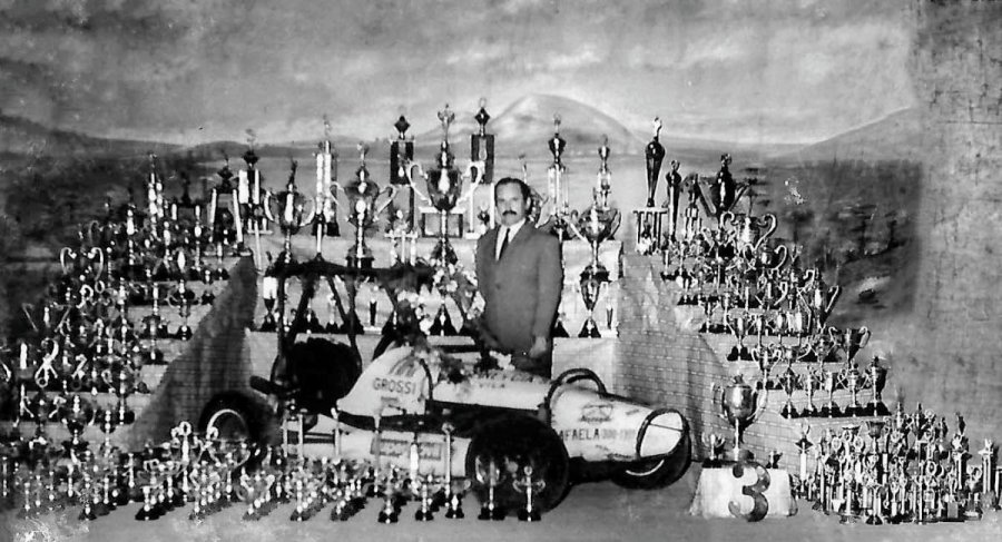 Octavio Bessone con uno de sus autos y rodeado de sus trofeos.