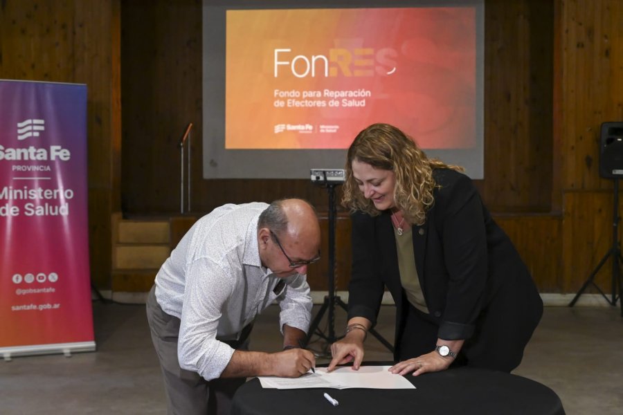 Hugo Michelini firma el acuerdo y observa Silvia Ciancio.