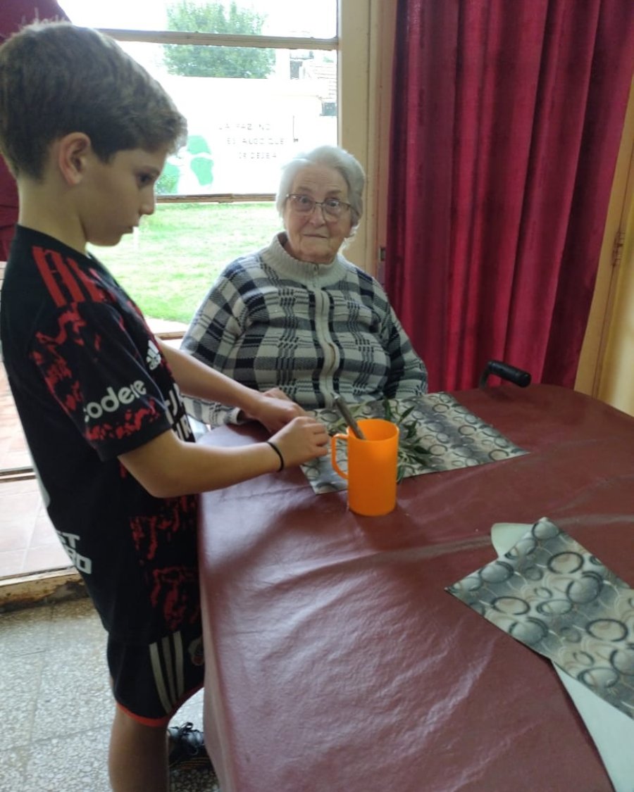 uno de los niños de catequesis junto a una de las residentes en el hogar.