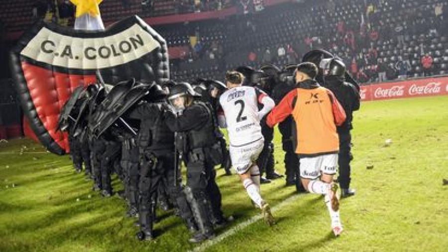 VIOLENCIA. Los jugadores locales debieron dejar la cancha protegidos por la policía.
