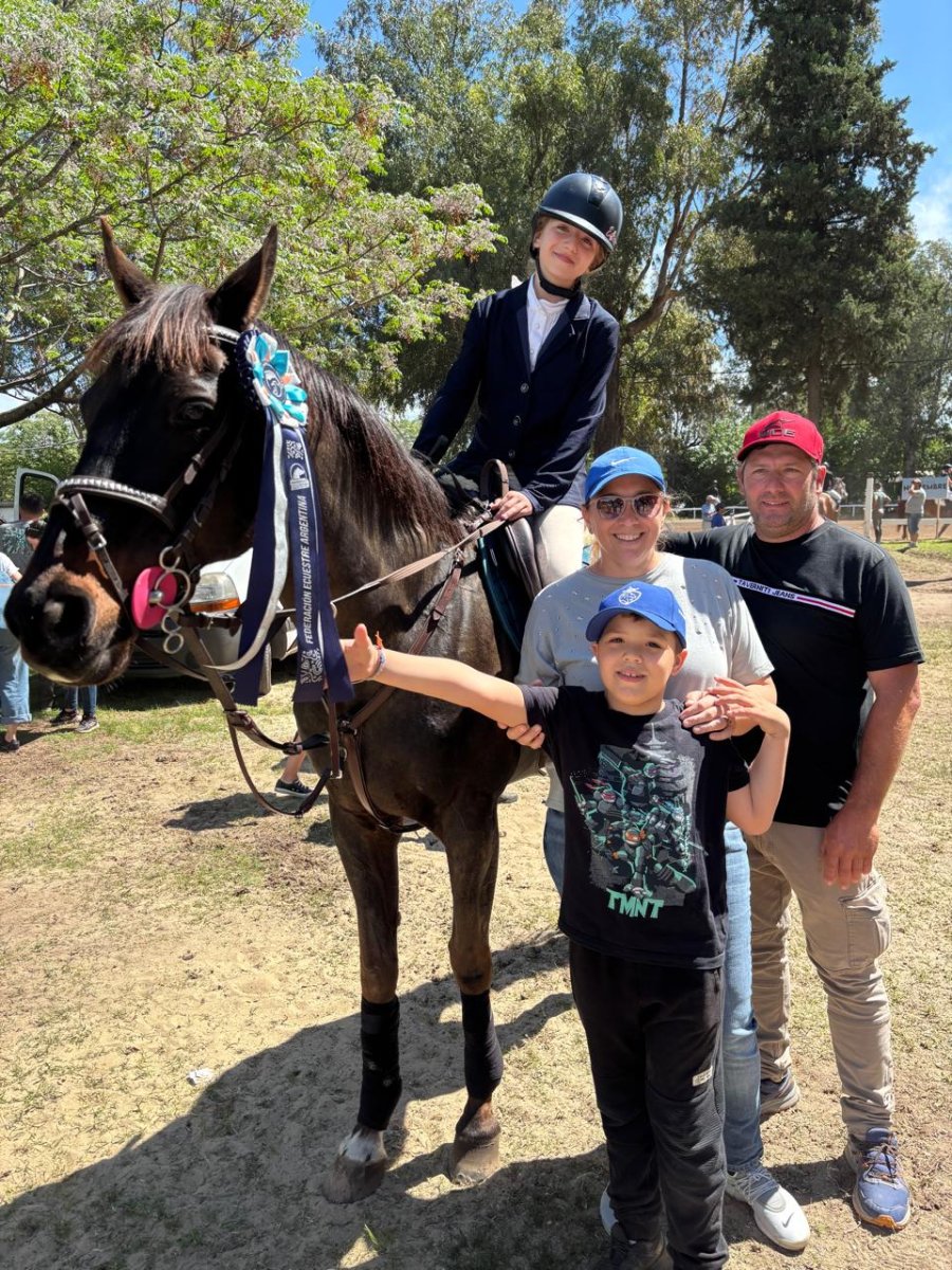 Emma con su caballo y cucarda,  acompañada de su mama Pia, su papa Pablo y su hermano Pedro.