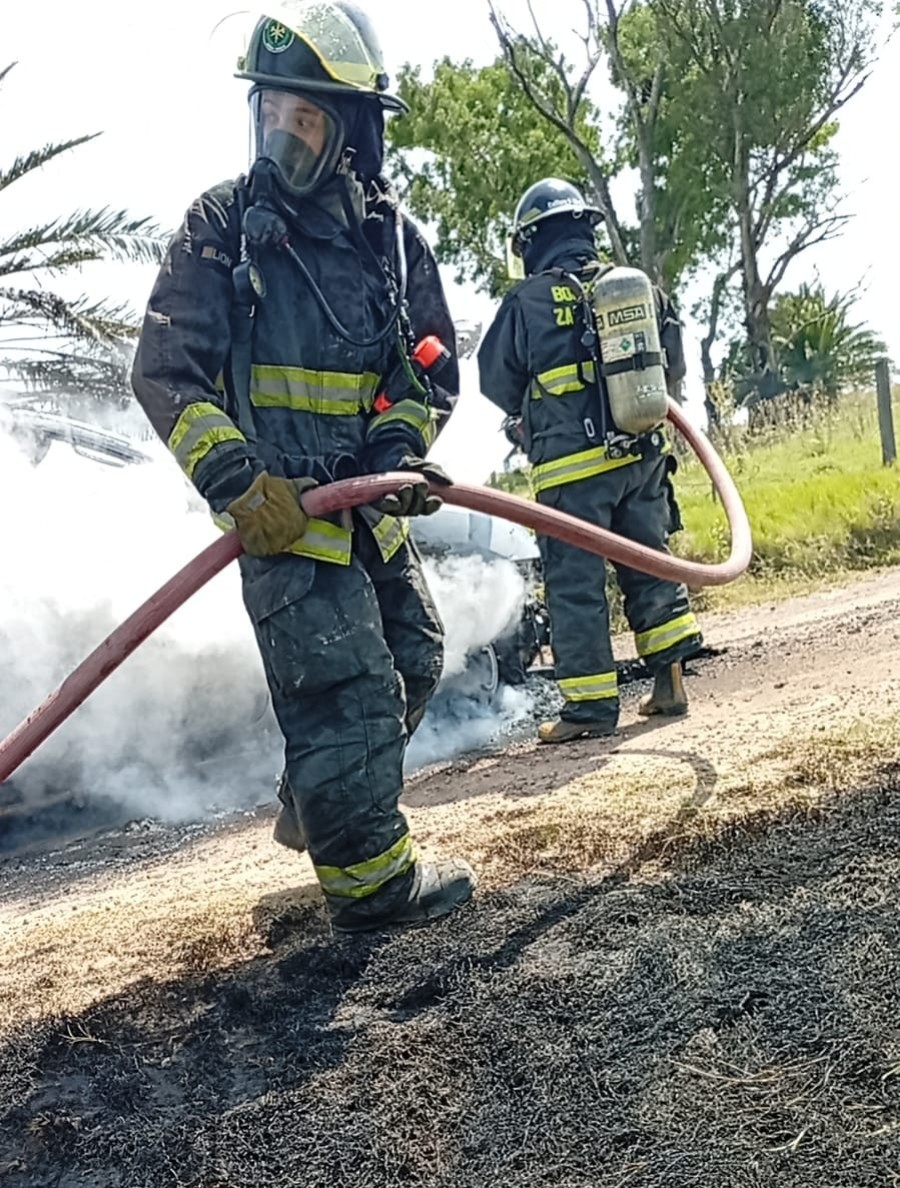 Bomberos durante las labores para extinguir el fuego en la camioneta y los pastos cercanos. (FOTO DGB)