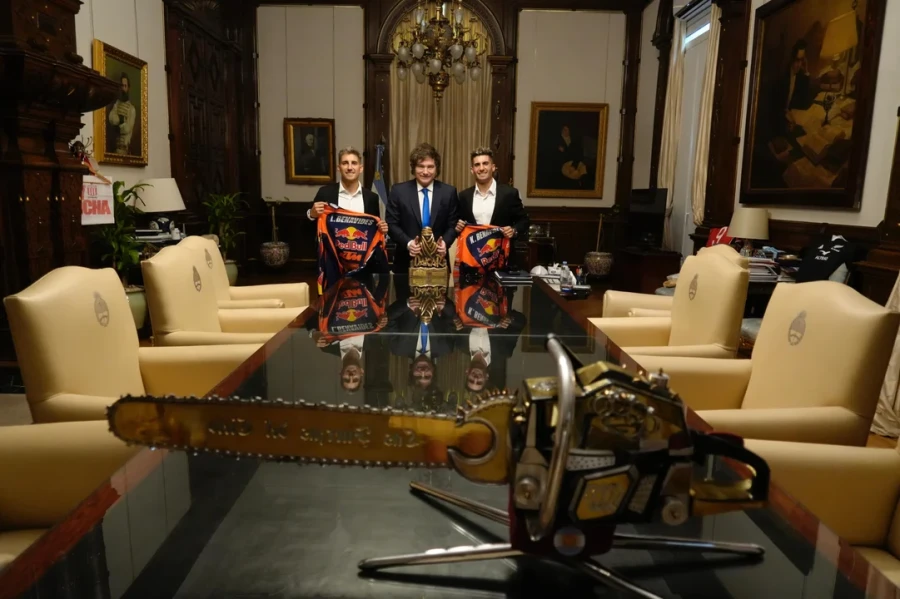 La motosierra, s&iacute;mbolo que representa el objetivo del Gobierno de reducir el gasto p&uacute;blico, en primer plano de una foto que muestra tambi&eacute;n al presidente Milei con los hermanos Benavides. (FOTO CASA ROSADA)