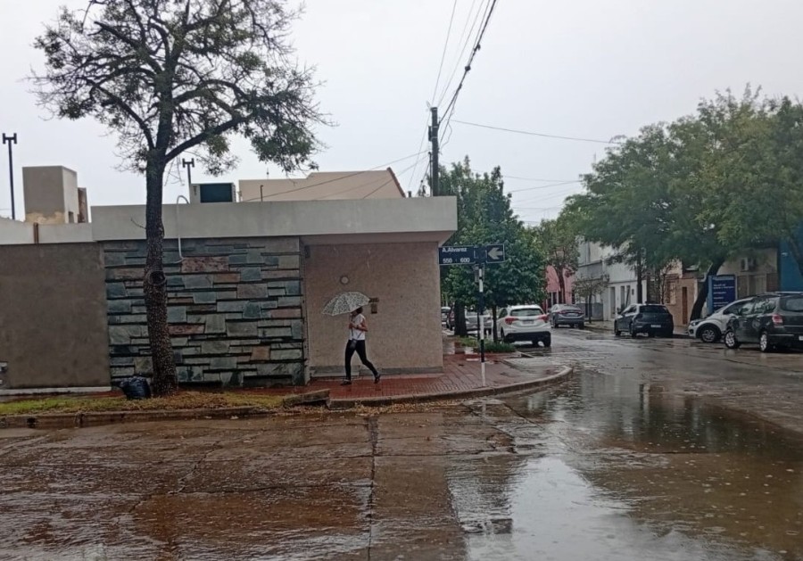 Una vecina camina por la vereda bajo la protecci&oacute;n de un paraguas en el mediod&iacute;a del lunes. (FOTO LA OPINI&Oacute;N)