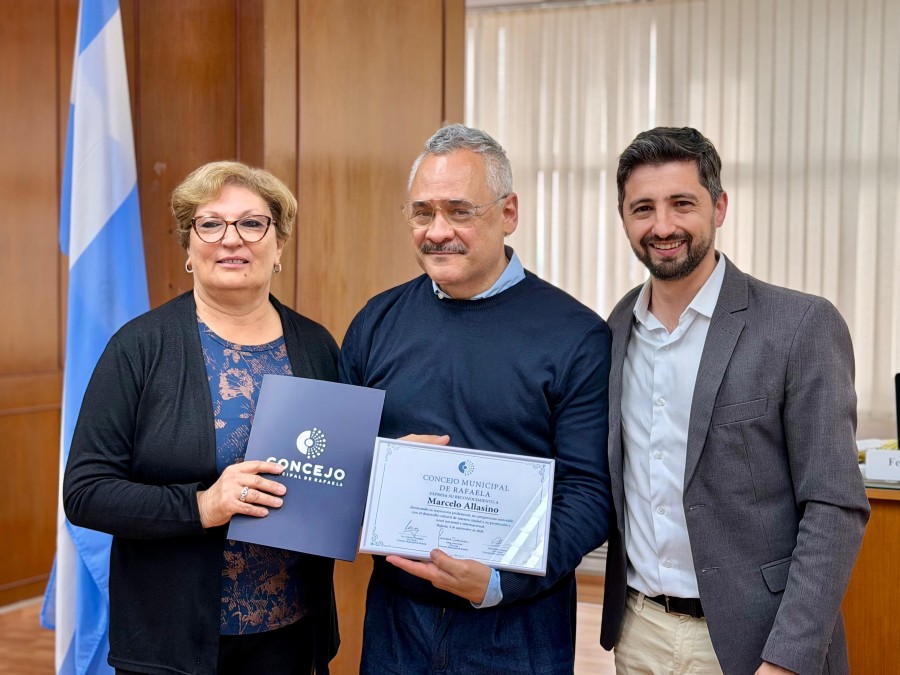 Mabel Fossatti y Juan Senn entregan una copia de la Declaraci&oacute;n que destaca la trayectoria de Marcelo Allasino en las artes esc&eacute;nicas. (FOTO PRENSA CONCEJO)